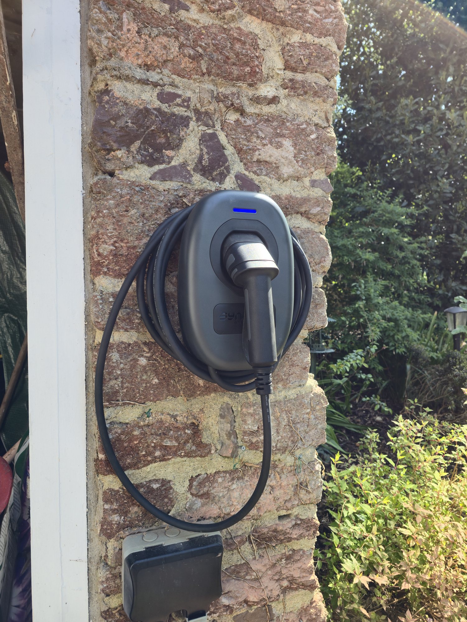 Home electric vehicle charger installed on a stone wall